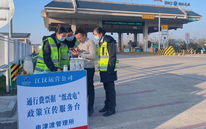 在申津渡收费站，工作人员向司乘人员宣传通行票据“纸改电”政策。